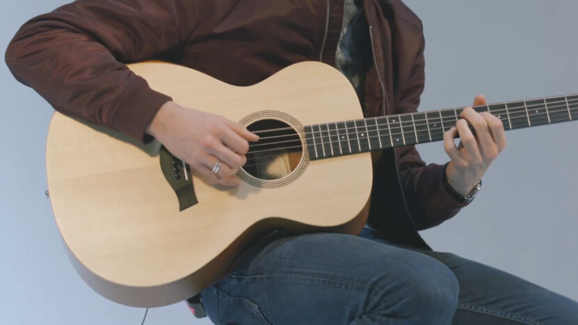 A guy playing the Academy 12e guitar